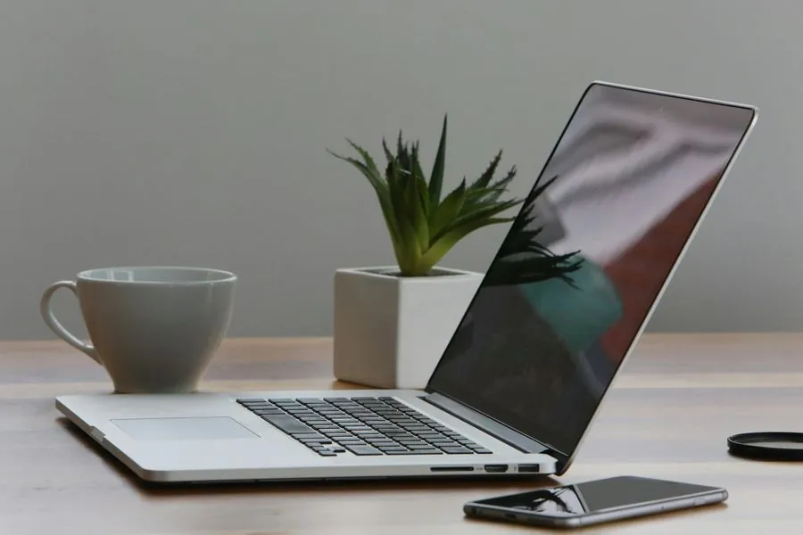 Laptop mỏng nhẹ đặt trên bàn làm việc cùng điện thoại, minh họa dịch vụ cầm laptop Hà Nội