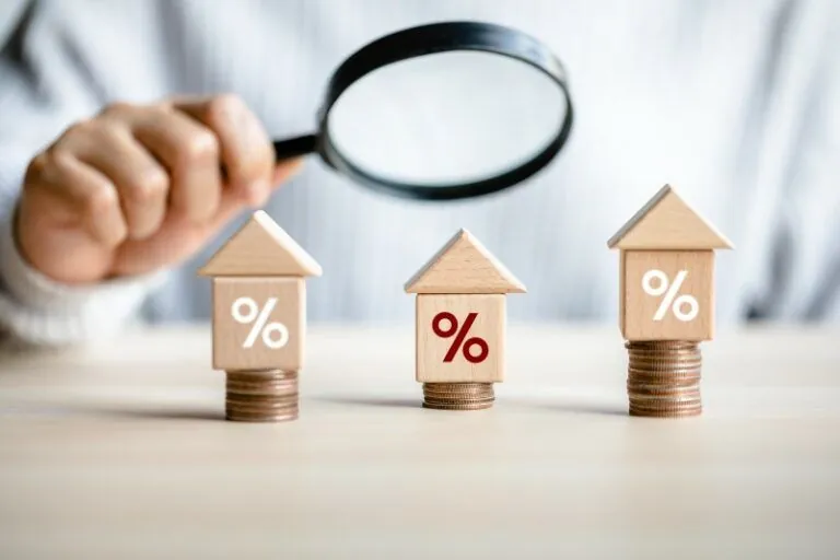 Kính lúp soi mức lãi suất trên mô hình nhà, minh họa lãi suất cầm sổ đỏ minh bạch
