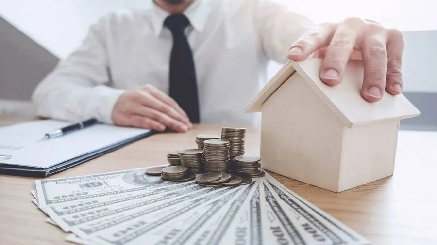 Mô hình ngôi nhà, đồng xu và tiền mặt trên bàn giao dịch, minh họa cầm đồ minh bạch